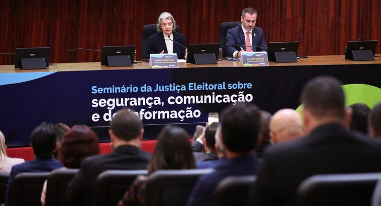 tse_seminario_desinformacao_capa_ #PraTodosVerem: Na fotografia aparece a Ministra Cármen Lúcia e um senhor de terno sentados à me...